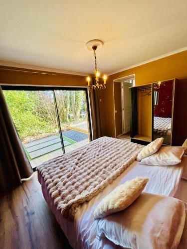 a bedroom with a large bed with a large window at Le Manoir de la belle epoque in Béthencourt-sur-Mer