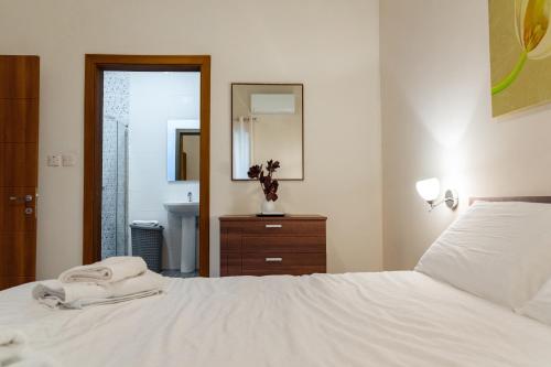 a bedroom with a white bed and a mirror at Your quiet retreat in Marsalforn in Marsalforn
