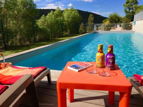 une table avec deux bouteilles dessus à côté d'une piscine dans l'établissement Neues, modernes Steinchalet mit grosser Terrasse und Pool bei Rondinara, à Bonifacio
