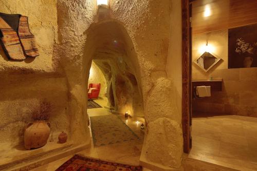 a bathroom with a stone hallway with a walk in shower at Jerveni Cave Hotel in Mustafapaşa