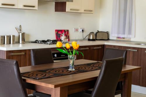 a kitchen table with a vase of yellow flowers on it at Your quiet retreat in Marsalforn in Marsalforn