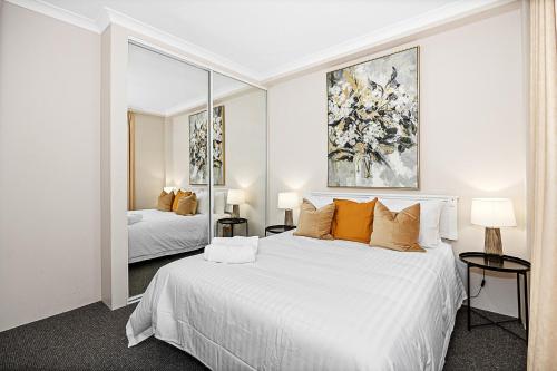 a white bedroom with two beds and a mirror at Pause & Play A Sepal Stay in Perth
