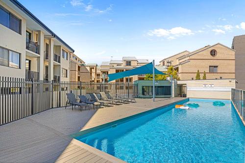 a swimming pool with chairs and a blue umbrella at Pause & Play A Sepal Stay in Perth