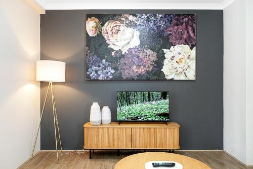 a living room with a tv and a painting on the wall at Pause & Play A Sepal Stay in Perth