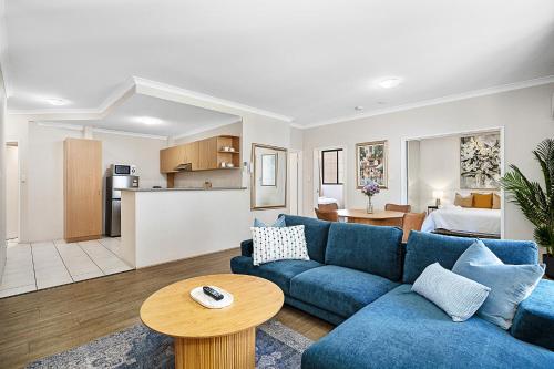 a living room with a blue couch and a kitchen at Pause & Play A Sepal Stay in Perth