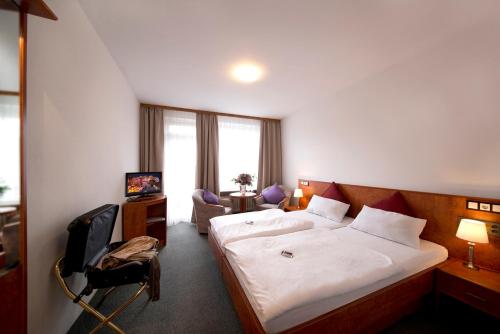 a hotel room with a bed and a chair at Hotel Heikenberg in Bad Lauterberg