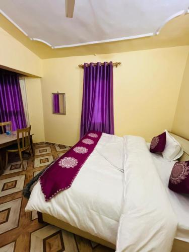 a bedroom with a large bed with purple curtains at The Hidden Cove in Bhīm Tāl