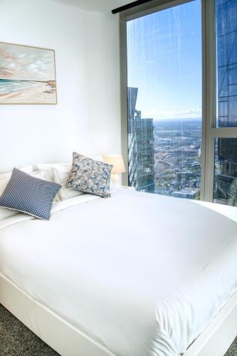 a white bed in a room with a large window at Park Avenue Melbourne in Melbourne