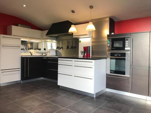 - une cuisine avec des appareils en noir et blanc et des murs rouges dans l'établissement Gite La Villa des Coeurs Vendéens, à Mortagne-sur-Sèvre