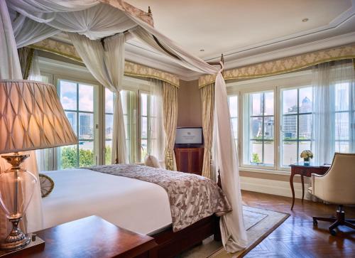 a bedroom with a bed and a desk and windows at Waldorf Astoria Shanghai on the Bund in Shanghai