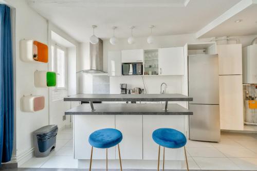 une cuisine avec des placards blancs et des tabourets bleus dans l'établissement GuestReady - Modern comfort in Les Batignolles, à Paris