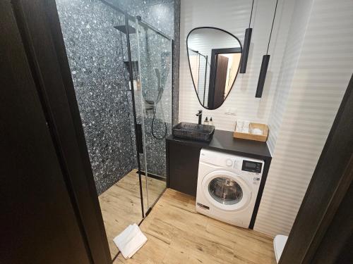 a bathroom with a washing machine and a mirror at F&R Sea Bliss Apartment in Gdańsk