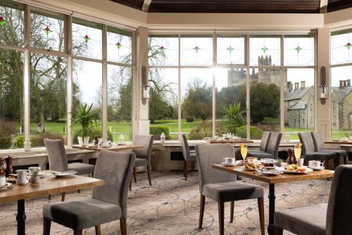 a restaurant with tables and chairs and large windows at The Lodges at Kilkea Castle in Kilkea