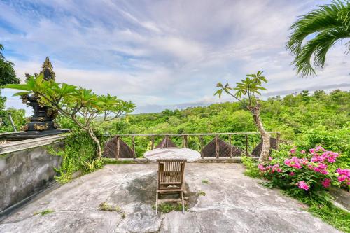 a chair sitting on a stone patio with trees and flowers at Innala Retreat Nusa Penida in Nusa Penida