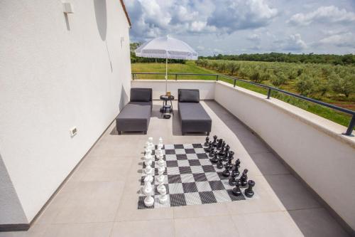 a balcony with a chess board and chairs and an umbrella at Villa Tiamo in Labinci