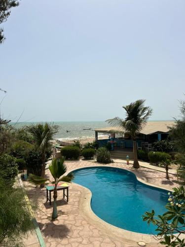 ein Swimmingpool mit dem Meer im Hintergrund in der Unterkunft Kernico in M'bour