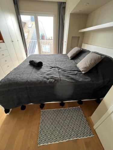 a large bed in a room with a large window at Très beau penthouse avec terrasse - Place Albert in Knokke-Heist