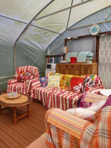 - un salon avec deux canapés et une horloge dans l'établissement Bell tent one of three to rent fully equipped private equipped kitchen tents too, à Saint-Michel-de-Montjoie