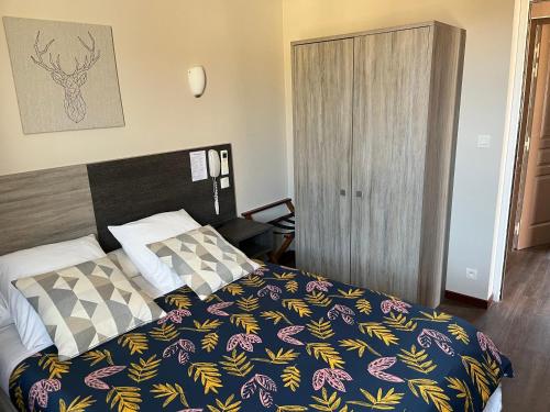 a bedroom with a bed with a colorful blanket at HOTEL LES MARRONNIERS in Thueyts