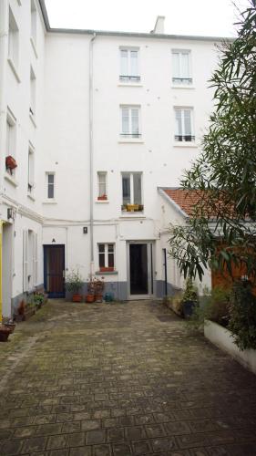 un grand bâtiment blanc avec une rue pavée dans l'établissement Peaceful studio in a impasse in Charonne, à Paris