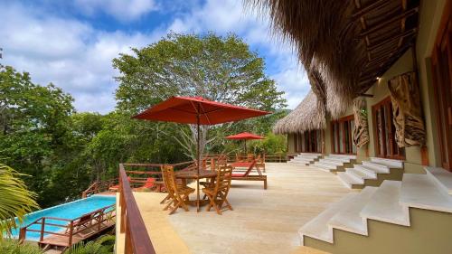a patio with tables and chairs and an umbrella at Senda Watapuy in El Zaino