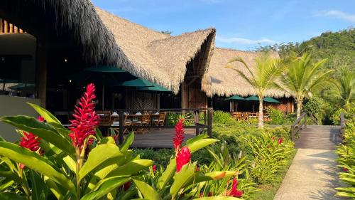 a resort with a thatched building with red flowers at Senda Watapuy in El Zaino
