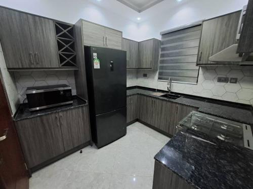 a kitchen with a black refrigerator and wooden cabinets at Holiday Home via Entebbe in Nalugala