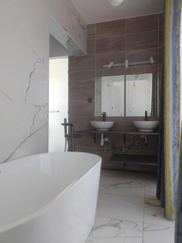 a bathroom with two sinks and a bath tub at Breakfast Included at Pes Villa Diani Beach in Diani Beach
