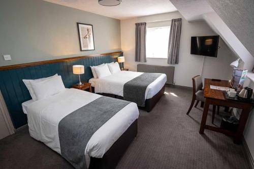 Una habitación de hotel con dos camas y un escritorio. en Cocked Hat by Greene King Inns, en Coventry