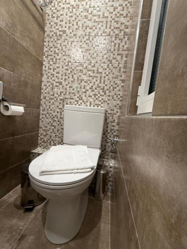 a bathroom with a white toilet and a tile wall at Glaros Hotel in Piraeus