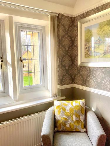 a living room with a chair and two windows at Southlands B&B in Bourton on the Water