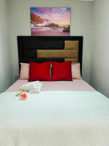 a bed with two red pillows and a rose on it at Ashridge Guesthouse & Safaris in Hazyview