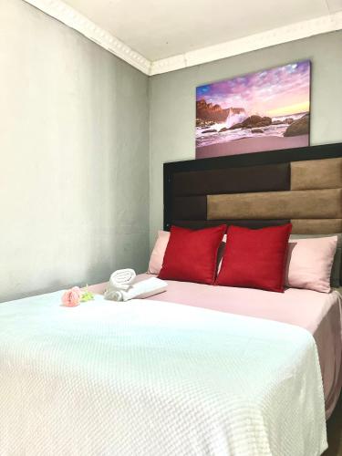 a bedroom with a large bed with red pillows at Ashridge Guesthouse & Safaris in Hazyview