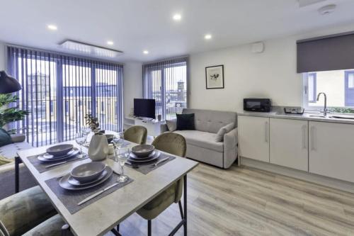 a kitchen and living room with a table and a couch at Stylish & Modern Flat 2 Min Walk to Ashford Outlet in Ashford