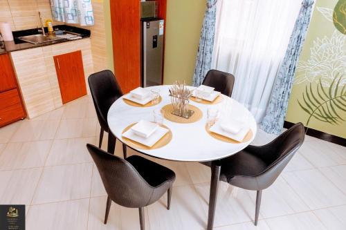 a white table with black chairs and a kitchen at Safa Homes and Residences in Kampala
