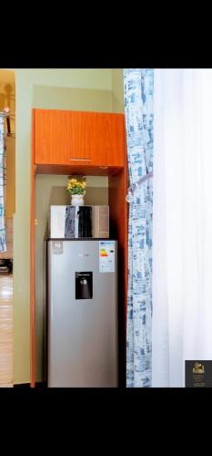a kitchen with a refrigerator with a microwave on top of it at Safa Homes and Residences in Kampala