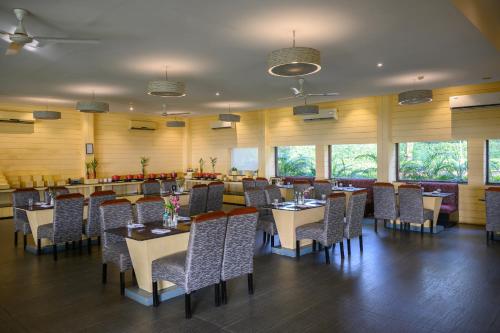 a dining room with tables and chairs and windows at Sinclairs Retreat Dooars, Chalsa in Chālsa