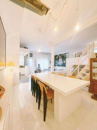 une grande cuisine blanche avec une grande table et des chaises blanches dans l'établissement Maison Antoinette Paris - Maison Nomade Chic, à Paris