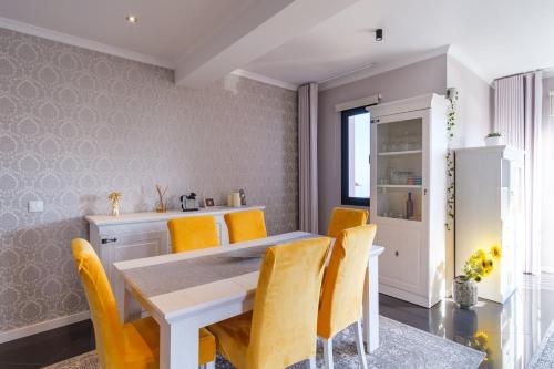 a dining room with a white table and yellow chairs at GuestReady - Private Terrace Stay in Funchal