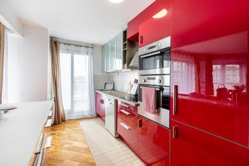 Il comprend une cuisine équipée de placards rouges et d'un réfrigérateur rouge. dans l'établissement GuestReady - Charming Family Duplex with a terrace, à Paris