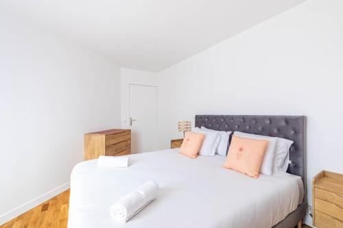 - une chambre dotée d'un lit blanc avec des oreillers orange et blanc dans l'établissement GuestReady - Charming Family Duplex with a terrace, à Paris