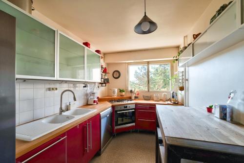 une cuisine avec des placards rouges et un comptoir en bois dans l'établissement GuestReady - Serene Retreat with a terrace, à Paris