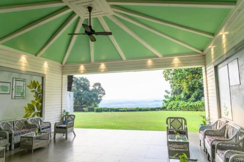 a screened porch with a ceiling fan and a view of a field at Sinclairs Retreat Dooars, Chalsa in Chālsa