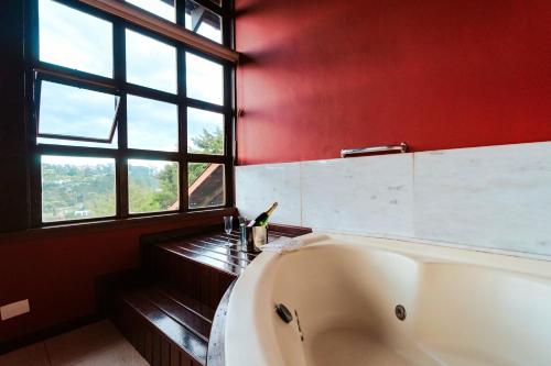 a bath tub in a bathroom with a red wall at Pousada Recanto dos Sonhos in Campos do Jordão
