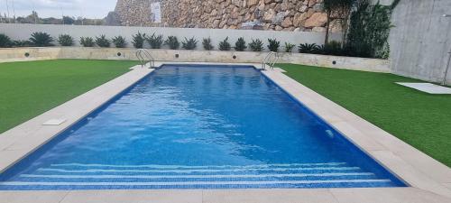 ein großer Pool mit blauem Wasser und Gras in der Unterkunft PREMIUM Magníficas Vistas Panorámicas con Terraza - By Aloha Palma in Águilas