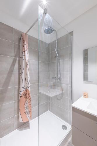 une douche avec une porte vitrée dans une salle de bain dans l'établissement Pau Standing & Confort, à Pau