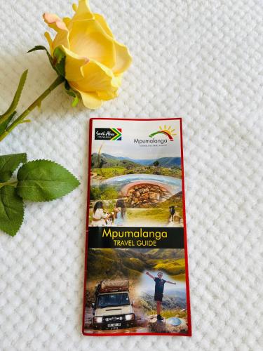 a magazine on a table with a yellow flower at Ashridge Guesthouse & Safaris in Hazyview