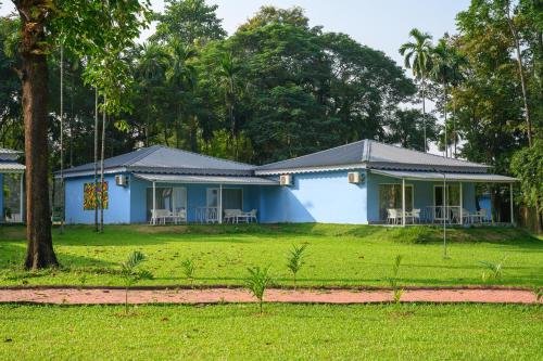 a blue house with tables and chairs in a yard at Sinclairs Retreat Dooars, Chalsa in Chālsa