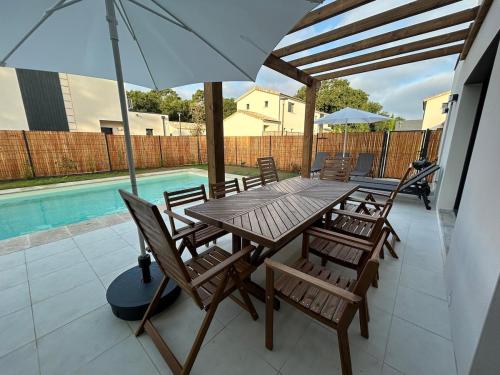 a wooden table and chairs with an umbrella on a patio at La Forêt d'Armotte villa 12 in Saint-Augustin