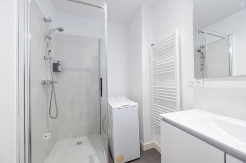 une salle de bain blanche avec une douche et un lavabo dans l'établissement Le Doux Séjour, à Pau